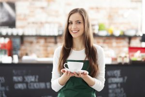 Waitress holding cup of coffee in cafe