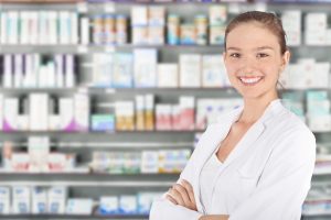 Young female smiling pharmacist standing in pharmacy